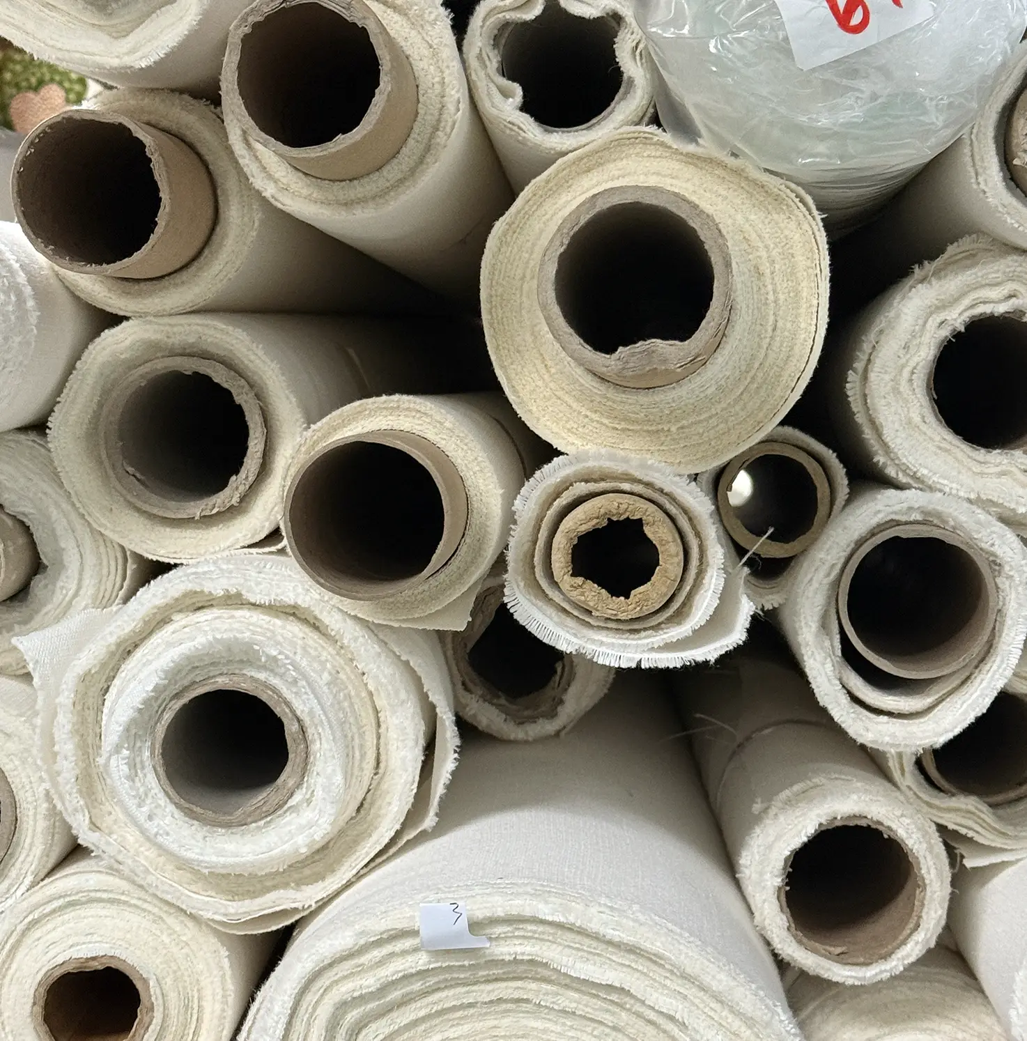 Rolls of stock fabrics piled on top of each other.